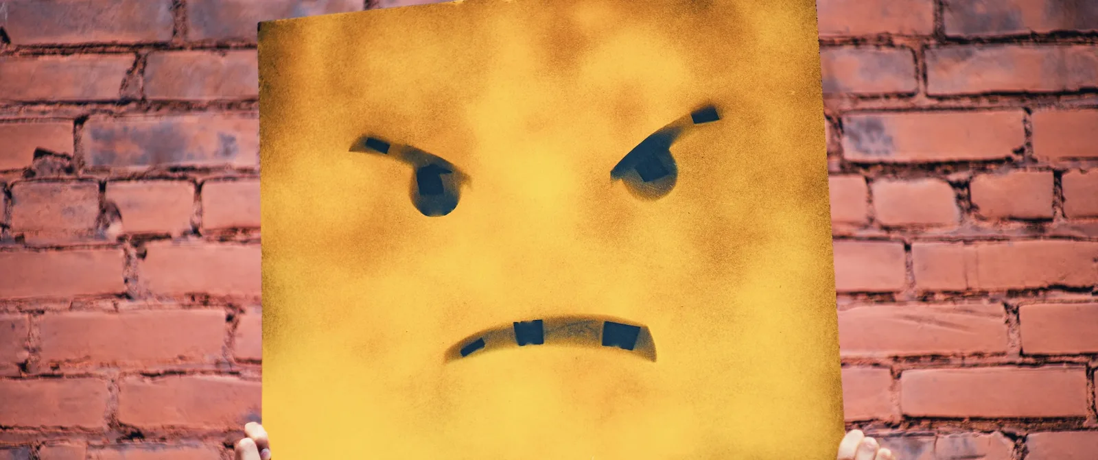 An angry face painted on a yellow piece of cardboard