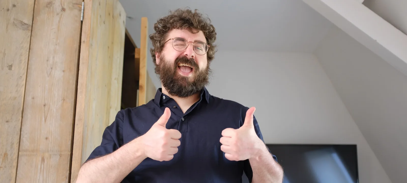A man with a beard giving two thumbs up