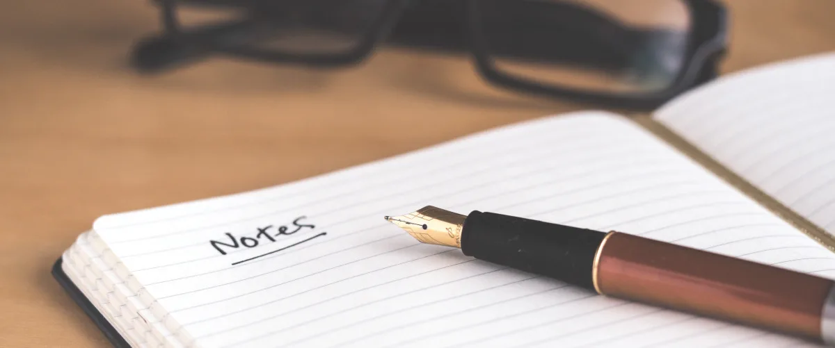A a pen resting on top of a notepad with the word "Notes" written on it.