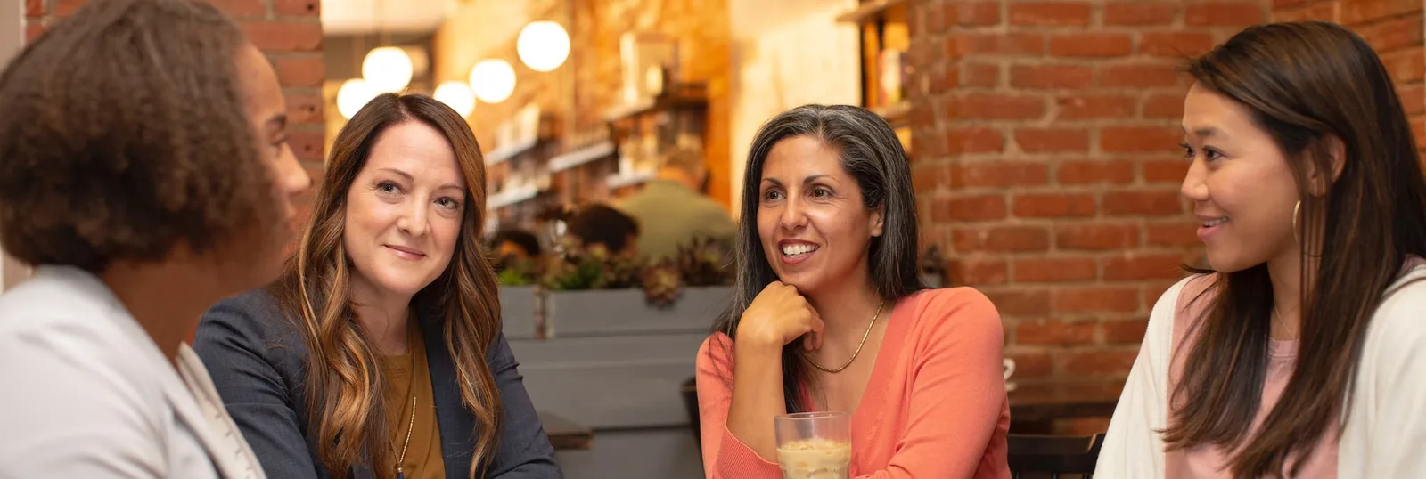 Four women sitting around a table talking